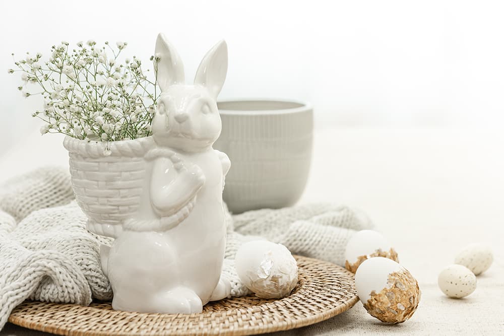 Fehér kerámia nyuszi, natúr textúrák és tojásdíszek alkotnak elegáns, világos tónusú húsvéti dekorációt