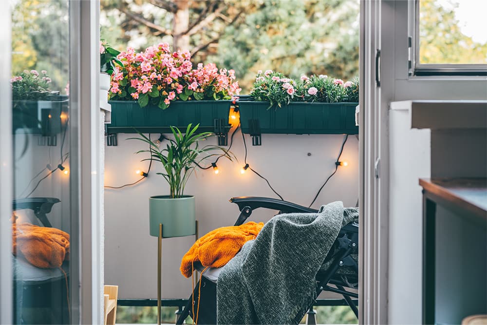 Hangulatos kis erkély virágládákkal, fényfüzérrel, pléddel és kényelmes pihenősarokkal